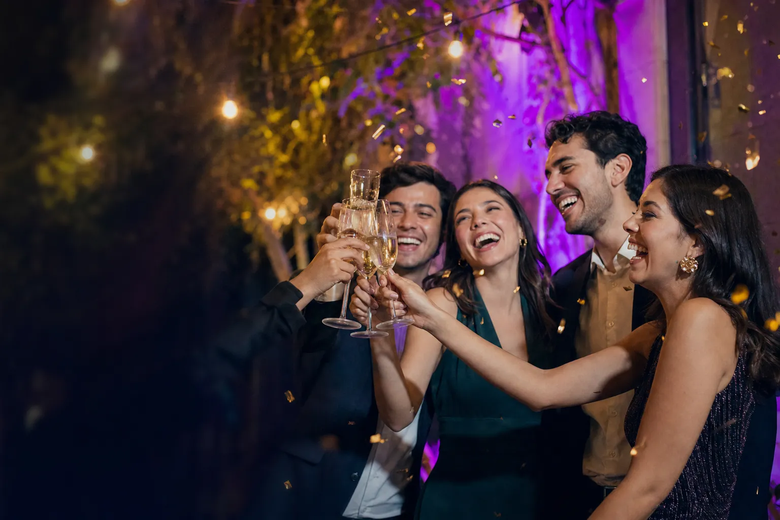 Un grupo de amigos brinda con champaña entre confeti durante una fiesta nocturna.
